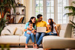 © StockImageFactory - Young family using laptop indoors on sofa for shopping, surfing, and spending time together happily