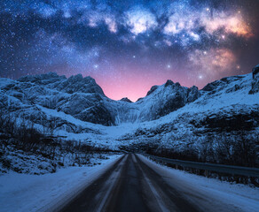 Wall Mural - glowing milky way over road, snowy mountains at winter starry night in lofoten, norway. pink sky wit
