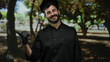 © Krakenimages.com - Man chef with beard smiling outdoors in a green park, wearing black uniform and gloves, surrounded by trees, showcasing a casual cooking environment.