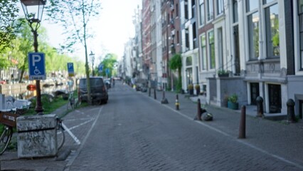Naklejka na meble Blurred street scene captures charming canals and classic architecture in amsterdam, netherlands, with a focus on bokeh effect and serene urban landscape.