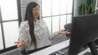 © Krakenimages.com - Woman gesturing in modern office with computer, wearing glasses and elegant white blouse, suggesting confusion or questioning during a work-related task, indoors.