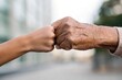 © Тетяна Костів - Elderly man and young person's hands meet in a supportive gesture during fitness training session outdoors