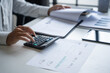 © Charlie's - Businessman Calculating Finances with Calculator in Modern Office.