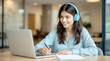 © Ada - Smiling girl wear wireless headphone study online with skype teacher, young woman with dark hair, wearing blue over-ear headphones and a light blue long-sleeved shirt