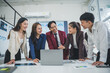 © Crystal - Asian businesspeople discussing a project using a laptop and analyzing graphs during a meeting in a modern office