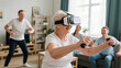 © AgungKY - Elderly woman enjoys VR headset experience while exercising with family at home