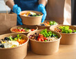 © Arda ALTAY - A person wearing blue gloves is carefully arranging colorful, fresh poke bowls filled with vegetables, greens, and proteins into eco-friendly containers for takeaway service.