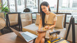 © dodotone - Entrepreneur woman young adult asian work business trip at cafe lounge meeting online digital tablet laptop with travel luggage positive smiling face