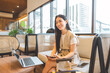 © dodotone - Entrepreneur woman young adult asian work business trip at cafe lounge using digital tablet laptop with travel luggage positive attitude smiling face