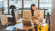 © dodotone - Entrepreneur woman young adult asian work business trip at cafe lounge meeting online digital tablet laptop with travel luggage positive smiling face
