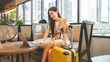 © dodotone - Entrepreneur woman young adult asian work business trip at cafe lounge meeting online digital tablet laptop with travel luggage positive smiling face
