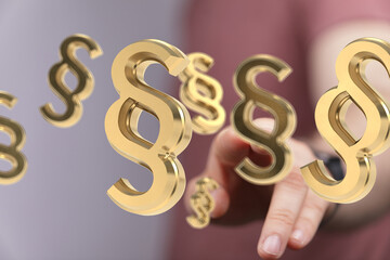 Aufkleber - Abstract image of 3D golden paragraph symbols floating towards a hand, symbolizing legal concepts.