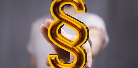 Aufkleber - Close-up of a hand holding a golden paragraph symbol.  Legal, law, justice concept.