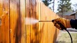 © Gophotograph - Detailed view of a person staining a wooden fence.