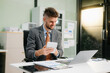 © Nuttapong punna - Confident businessman working on finance analysis with a tablet and laptop at office desk