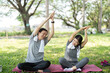 © Natee Meepian - Couple enjoying outdoor yoga stretches in a park