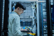 © reewungjunerr - Computer engineer is setting up network in server room,Systems Maintenance Technician,Male engineer working in server room at modern data center
