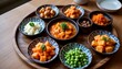 © Supaporn - side dish set with kimchi and banchan arranged in round plates on wooden tray, modern korean table setting