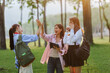 © Crystal - Group of young asian students celebrating success outdoors giving high five, holding books and tablet