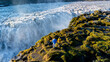 © Fokke Baarssen - Witness breathtaking Dettifoss waterfall in Iceland, where travelers stand in awe of the powerful cascade. Surrounded by moss and rugged terrain, the beauty of nature shines at sunrise.