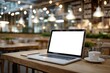 © whitestorm - Laptop with a blank screen on a wooden table in a cozy cafe, perfect for remote work or online meetings, with a cup of coffee and warm lighting adding to the ambiance.