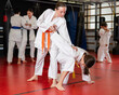 © JackF - Two teenage girls in kimonos train judo techniques in group in studio