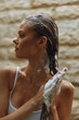 © SHOTPRIME STUDIO - woman washing long hair with shampoo foam, natural light, side profile, warm tones, gentle skincare routine, indoor bathroom setting