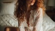 © Justlight - Sensual young woman with long red hair wearing white lace lingerie sitting on a bed in a bedroom, enjoying a moment of relaxation and intimacy