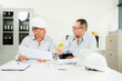 © Nuttapong punna - Construction engineers reviewing blueprints and tablet at desk. Team collaboration and planning for architecture or renovation project