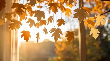 warm golden maple leaf garland decorates a window with sunshine light, creating cozy autumn home atm