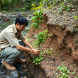 © Michael - A volunteer guy plants a tree along a stream to prevent erosion. The concept of ecology, environmental protection.