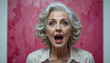 © DhanShalik - Surprised Senior: Expressive portrait of senior with open mouth, her eyes wide with surprise and shock. Set against an vibrant abstract pink background.