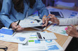 © crizzystudio - Businesswomen working with financial charts and calculator in office at night