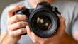 © PaulShlykov - Person holding a professional camera ready to take a photograph with a close-up lens view