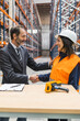 © Koldo_Studio - Manager and woman warehouse worker shaking hands in a bustling logistics center, symbolizing partnership and mutual respect in the industry