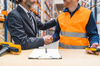 © Koldo_Studio - Manager and warehouse worker shaking hands after finalizing a successful deal in a bustling logistics center, celebrating partnership and teamwork
