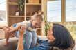 © Srdjan - Single mother and young daughter playing airplane game at home. Loving, joyful, creative interaction between parent and child, building trust and strong family bonds in a warm, sunlit living room