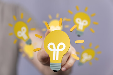 Aufkleber - Person's fingertip touches a glowing lightbulb, symbolizing innovation and ideas.