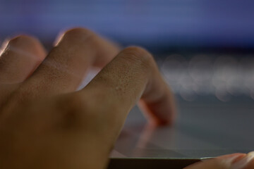 close-up of a hand in motion while typing on a laptop, illuminated by blue light from the screen. a 