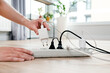 © Proxima Studio - Person is plugging in a device to a power strip
