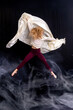 © dfriend150 - captures a dancer in a graceful pose on a black box against a dark backdrop. Dressed in a light gray sweater and maroon leggings, the dancer extends their arms upward while maintaining balance with on