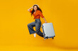 © Home-stock - Cheerful lady traveler jumping with suitcase over orange background, woman in straw hat having fun, enjoying vacation time, full length, free space