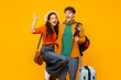 © Home-stock - Excited European couple with suitcase and tickets making victory gesture, ready for vacation, posing on yellow studio background