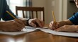 © Cintia - An adult assists a child with their homework at a wooden table, both writing with pencils on separate sheets of paper.