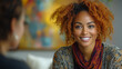 © Mas - Smiling woman with curly hair talks indoors with blurred background