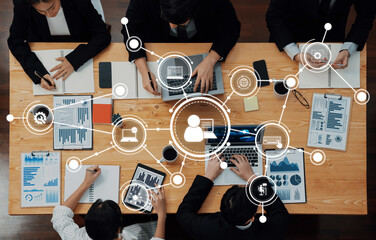 a top view of business professionals engaged in a meeting surrounded by laptops, documents, and digi