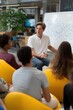 © Iryna - Young caucasian male leading interactive workshop with diverse young adults in modern office