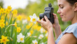 © Наталья Никитина - Woman photographing white flower among yellow daffodils in garden