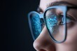 © Digital Design - Close-up of a person's face wearing glasses reflecting blue computer code, symbolizing technology and programming focus.