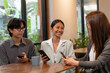 © Jestercine - Asian professionals sitting together at a cafe table, checking smartphones and sharing business ideas during an informal team meeting. Concept of modern teamwork and digital collaboration.